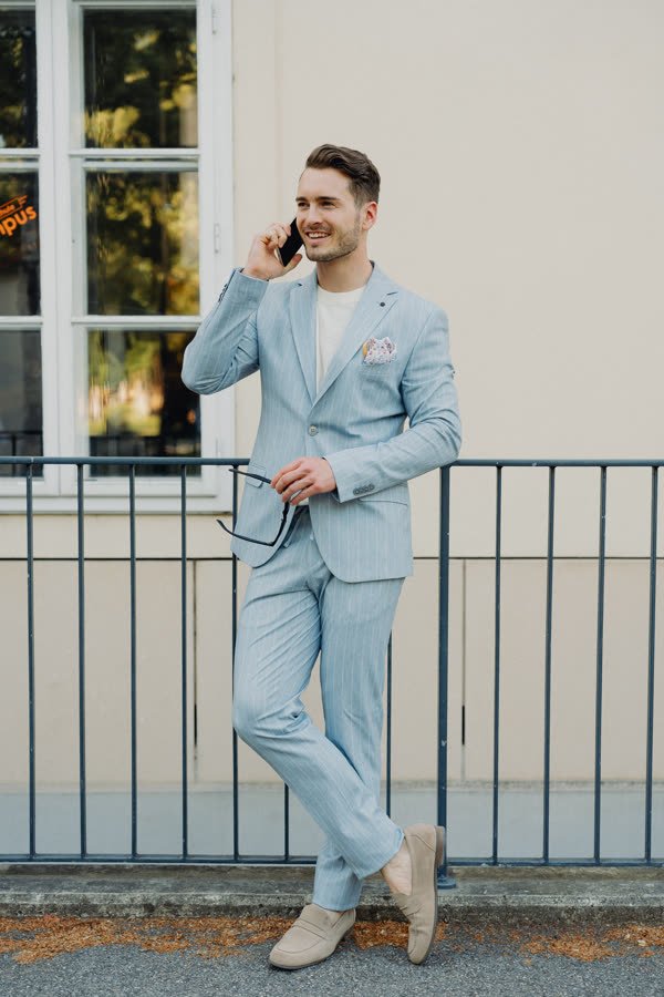Andreas Schmid, light blue suit, full length by a railing