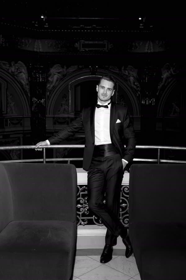 Andreas Schmid, black and white photo in a tuxedo in a museum hall
