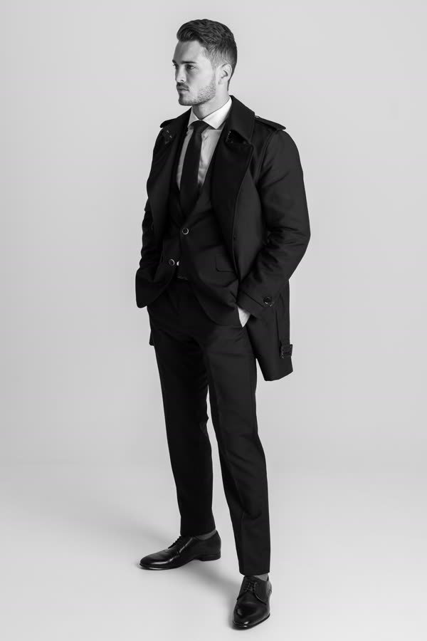 Andreas Schmid, black and white studio photo in a trench coat and tie